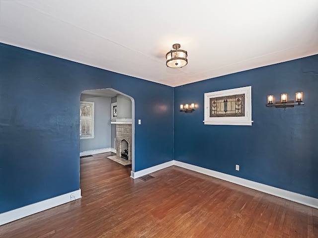 unfurnished room featuring dark hardwood / wood-style flooring and a brick fireplace