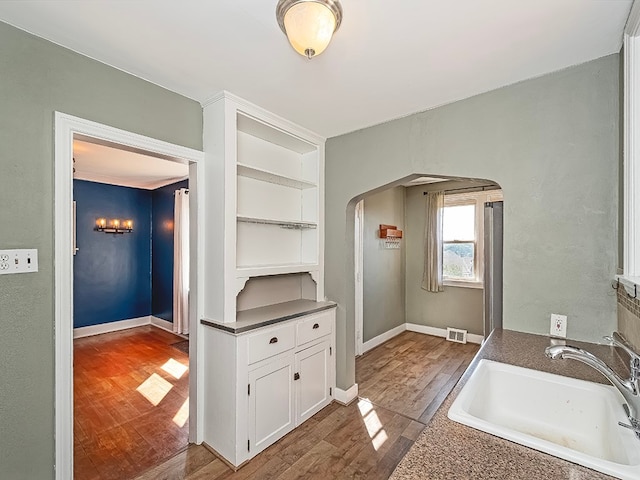 kitchen with hardwood / wood-style floors, sink, and white cabinets