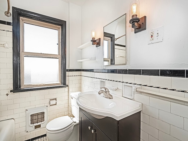 bathroom with a wealth of natural light, vanity, toilet, and tile walls