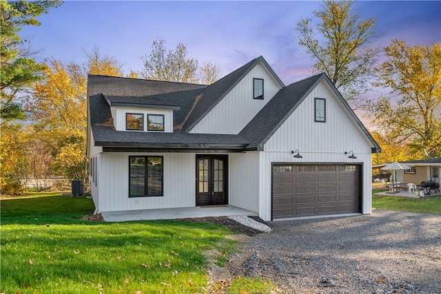 modern farmhouse style home with a garage, cooling unit, a lawn, and french doors