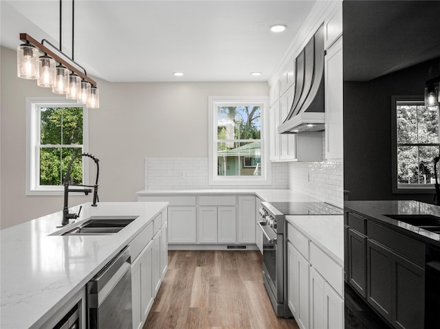 kitchen with pendant lighting, appliances with stainless steel finishes, light stone counters, and plenty of natural light