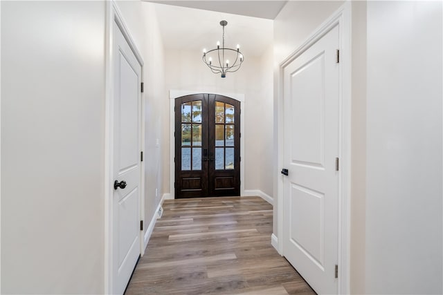 foyer entrance with a chandelier, light wood-type flooring, and french doors