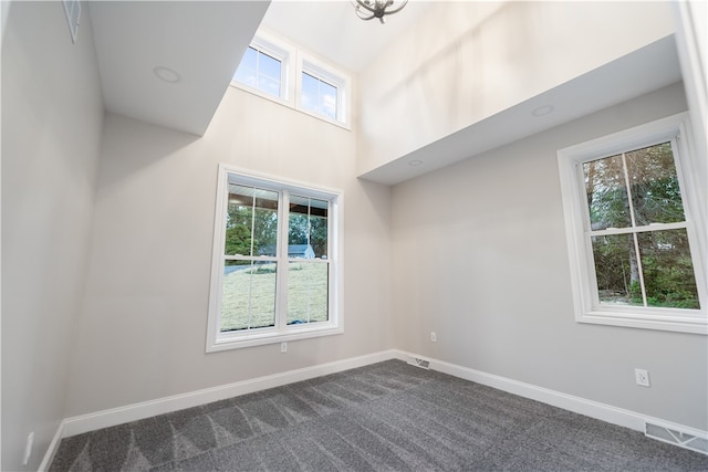 carpeted empty room featuring a high ceiling