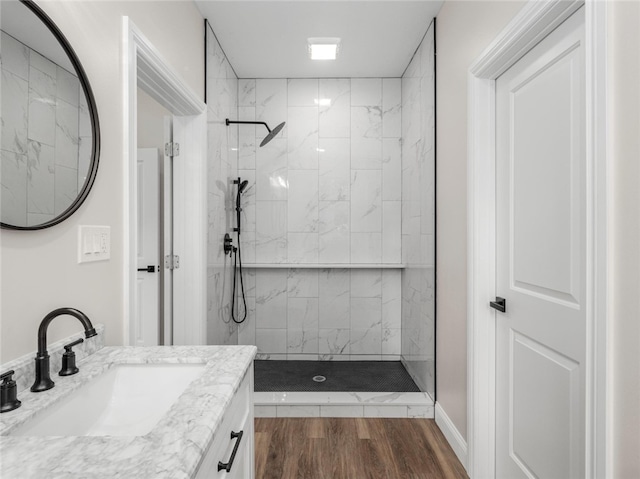 bathroom with wood-type flooring, a tile shower, and vanity