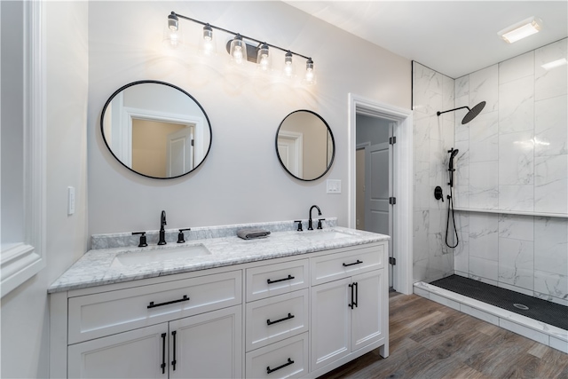 bathroom with wood-type flooring, a tile shower, and vanity