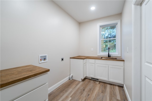 clothes washing area with hookup for an electric dryer, cabinets, sink, washer hookup, and light wood-type flooring