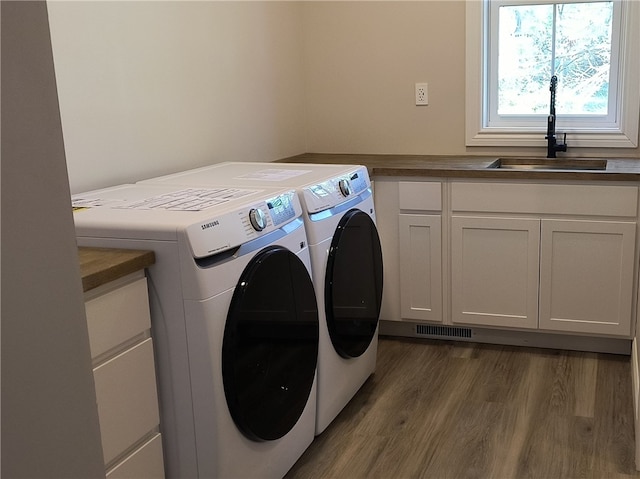 laundry area featuring cabinets, dark hardwood / wood-style flooring, sink, and washer and clothes dryer