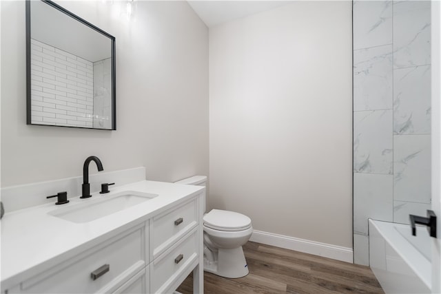 full bathroom with hardwood / wood-style floors, vanity, tiled shower / bath combo, and toilet