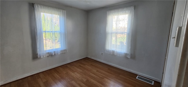 spare room featuring hardwood / wood-style floors and plenty of natural light