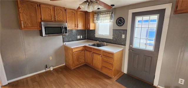 kitchen featuring sink, tasteful backsplash, ceiling fan, light hardwood / wood-style flooring, and decorative light fixtures