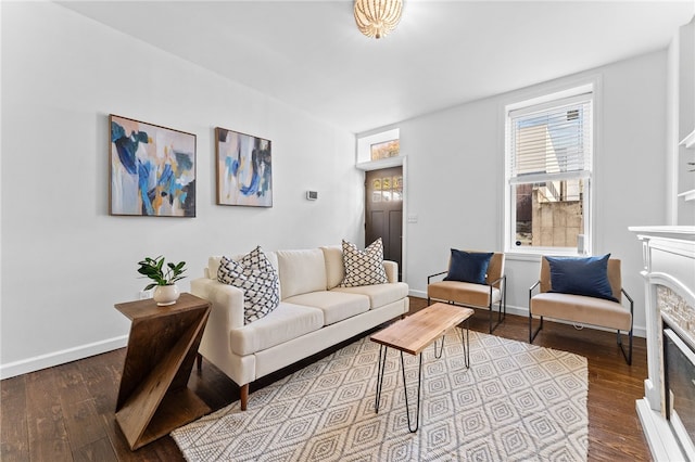 living area featuring dark wood-style floors, a glass covered fireplace, and baseboards