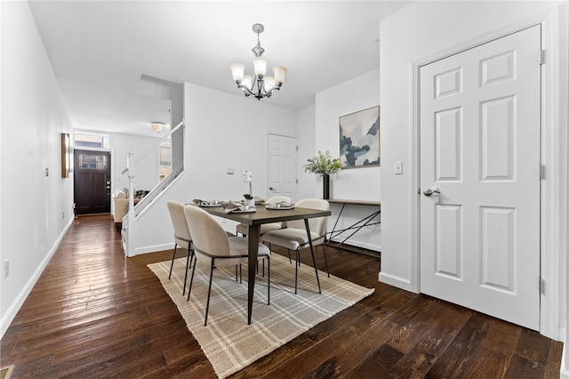 dining area with dark wood-type flooring and an inviting chandelier