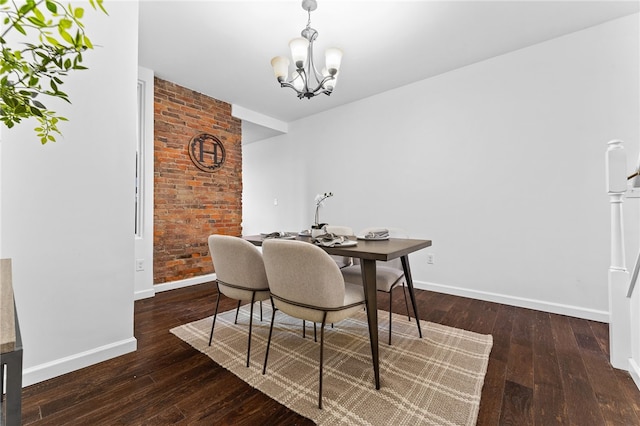 dining room with dark wood-type flooring, brick wall, and a notable chandelier