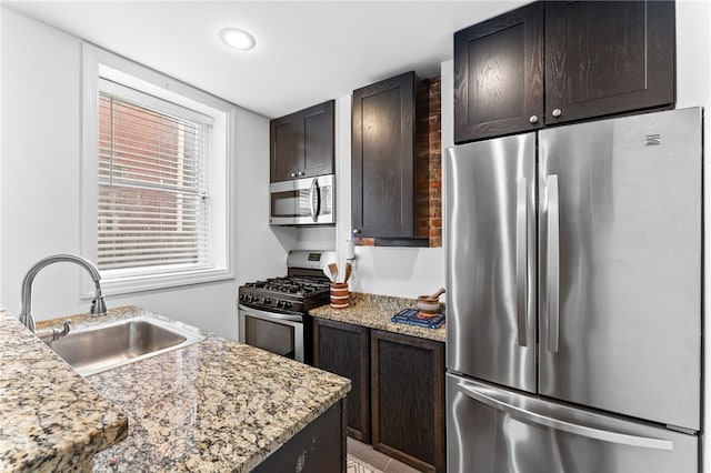 kitchen featuring dark brown cabinetry, appliances with stainless steel finishes, sink, and light stone countertops