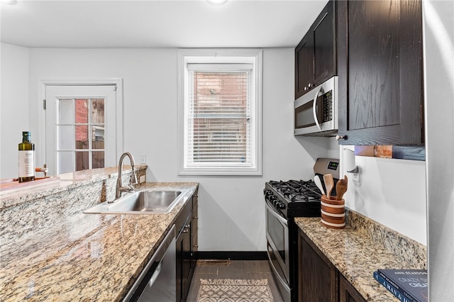 kitchen featuring stainless steel appliances, sink, light stone counters, dark hardwood / wood-style floors, and dark brown cabinets