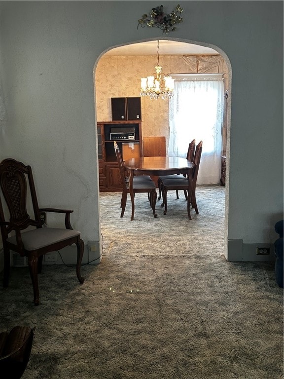 dining space featuring carpet and a notable chandelier