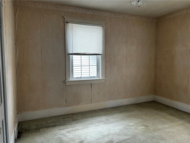 spare room featuring wood walls and light colored carpet