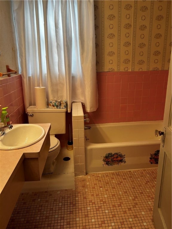 bathroom featuring a tub to relax in, vanity, toilet, and tile walls