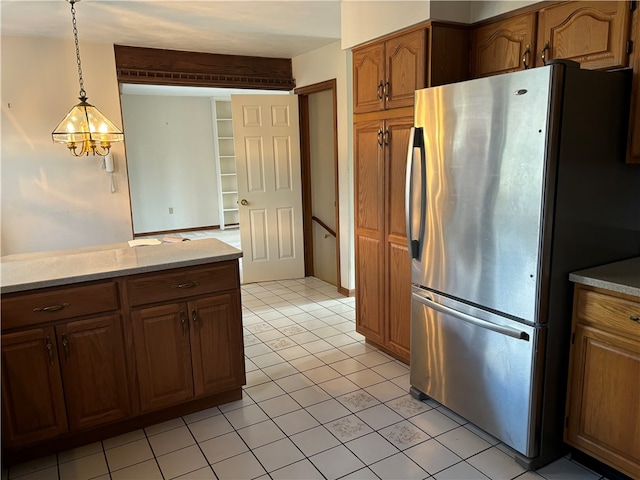 kitchen featuring light tile patterned flooring, stainless steel refrigerator, pendant lighting, light stone countertops, and a chandelier