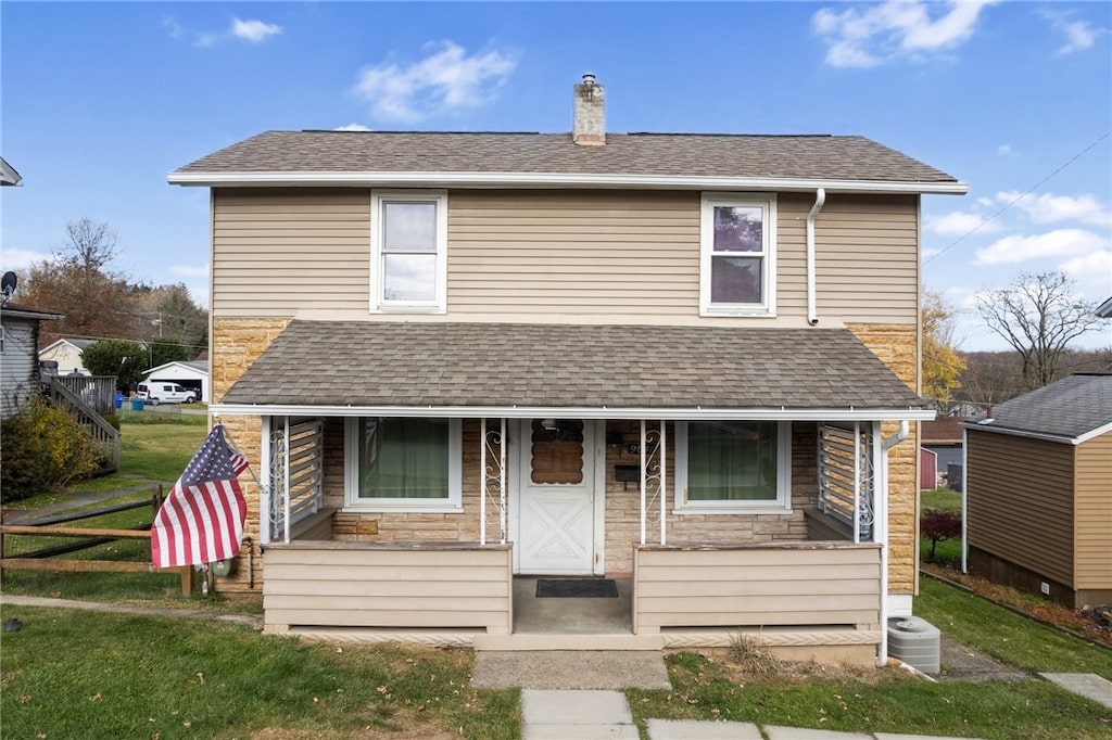 view of front of home featuring a front lawn, cooling unit, and a porch