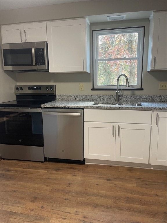 kitchen featuring white cabinetry, appliances with stainless steel finishes, sink, and light hardwood / wood-style flooring