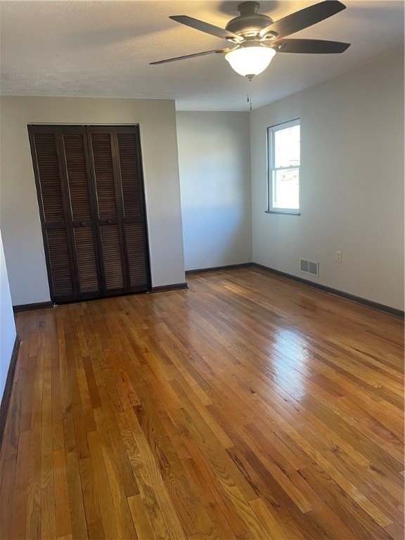 unfurnished bedroom featuring hardwood / wood-style floors, ceiling fan, and a textured ceiling