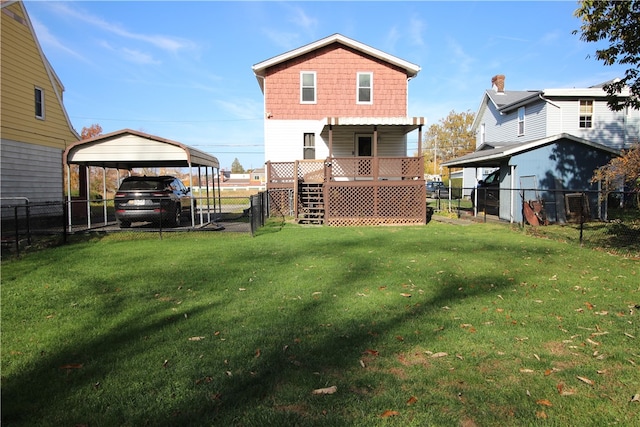 back of property with a deck, a lawn, and a carport