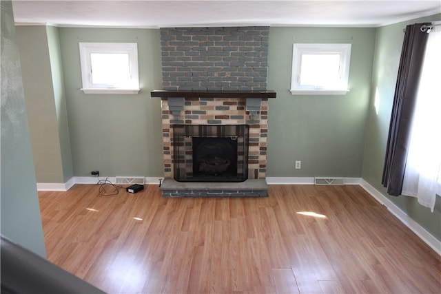 unfurnished living room with a wealth of natural light, a fireplace, and light wood-type flooring