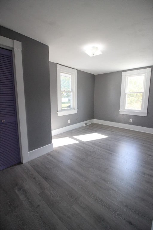 unfurnished room with dark hardwood / wood-style flooring and a healthy amount of sunlight