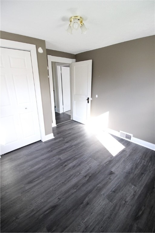 unfurnished bedroom featuring a closet and dark wood-type flooring