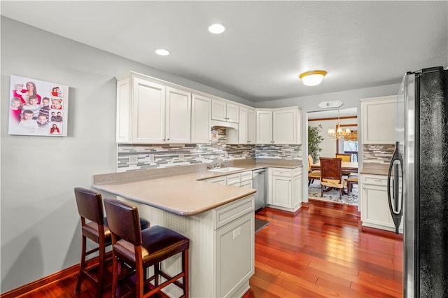 kitchen featuring stainless steel appliances, hardwood / wood-style flooring, white cabinetry, kitchen peninsula, and pendant lighting