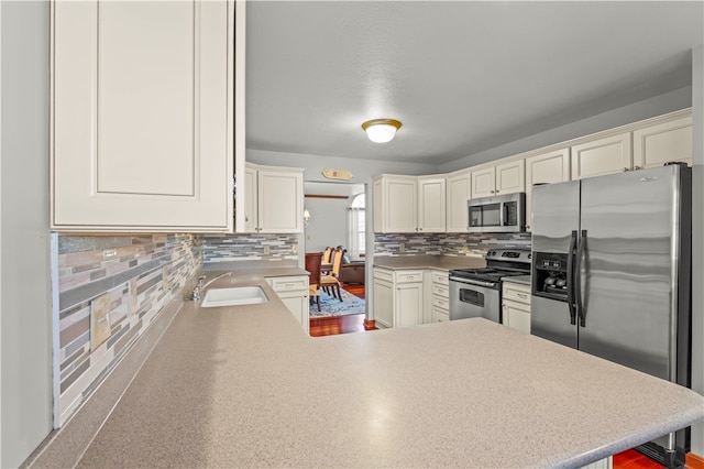 kitchen featuring kitchen peninsula, sink, appliances with stainless steel finishes, and tasteful backsplash