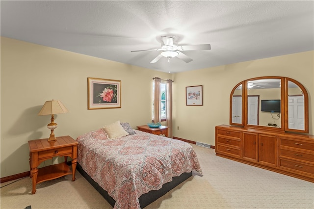 bedroom featuring a textured ceiling, light carpet, and ceiling fan