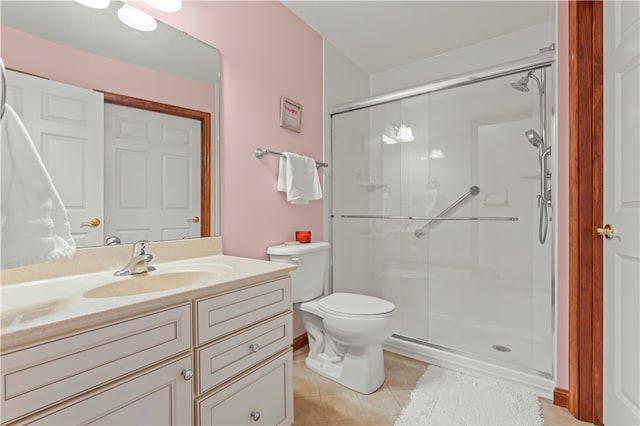 bathroom featuring toilet, vanity, tile patterned floors, and a shower with shower door