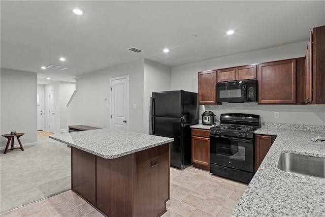 kitchen featuring black appliances, light stone counters, sink, and light carpet