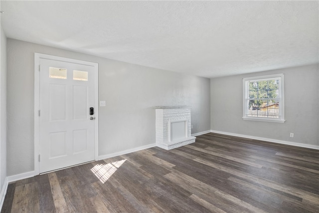 foyer entrance featuring dark wood-type flooring, a textured ceiling, and a fireplace