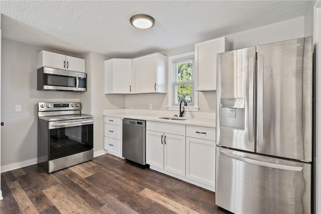 kitchen featuring stainless steel appliances, white cabinetry, a textured ceiling, dark hardwood / wood-style floors, and sink