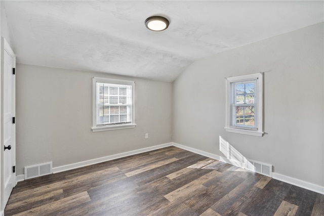 spare room with lofted ceiling, a healthy amount of sunlight, and dark hardwood / wood-style flooring