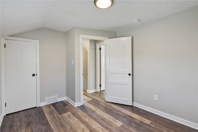 unfurnished bedroom with dark hardwood / wood-style flooring and lofted ceiling