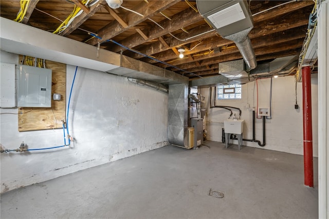 basement featuring electric panel, heating unit, and sink