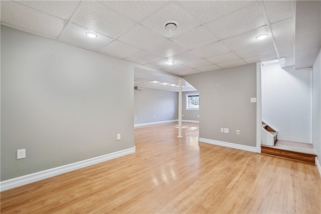 basement featuring a paneled ceiling and light wood-type flooring