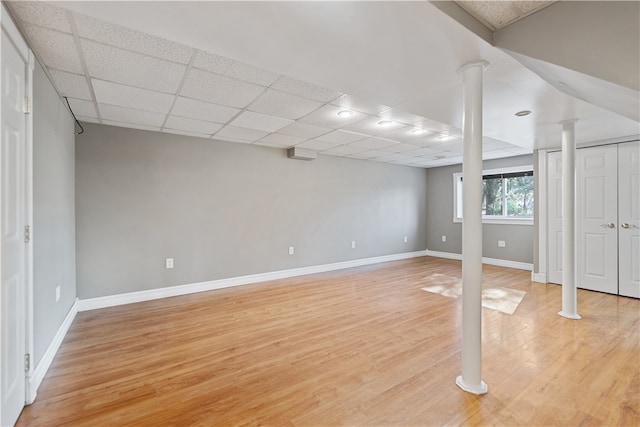 basement with a paneled ceiling and light hardwood / wood-style flooring