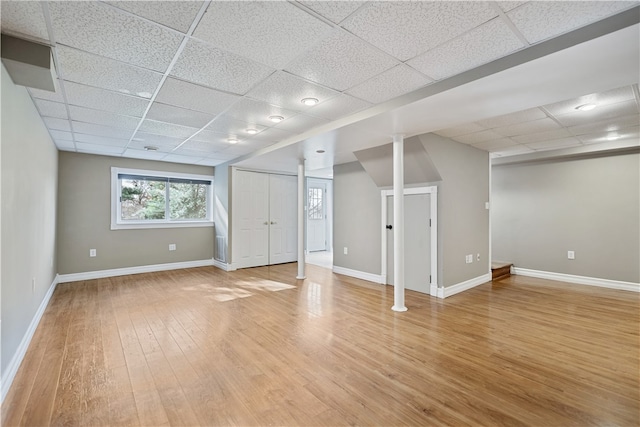 basement with light wood-type flooring and a paneled ceiling