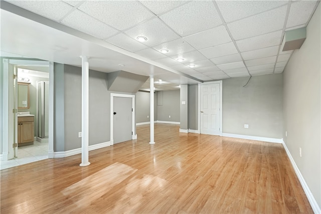 basement with a drop ceiling and light hardwood / wood-style floors