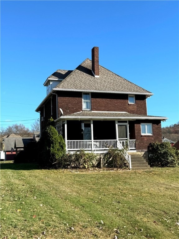 rear view of property featuring a lawn and covered porch