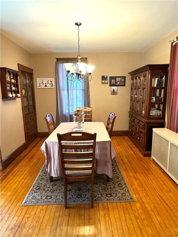 dining area featuring radiator, a notable chandelier, and light hardwood / wood-style floors