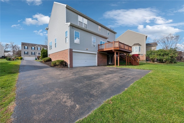 back of property featuring a garage, a lawn, and a deck