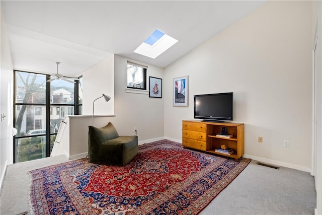 carpeted living room featuring ceiling fan and lofted ceiling with skylight