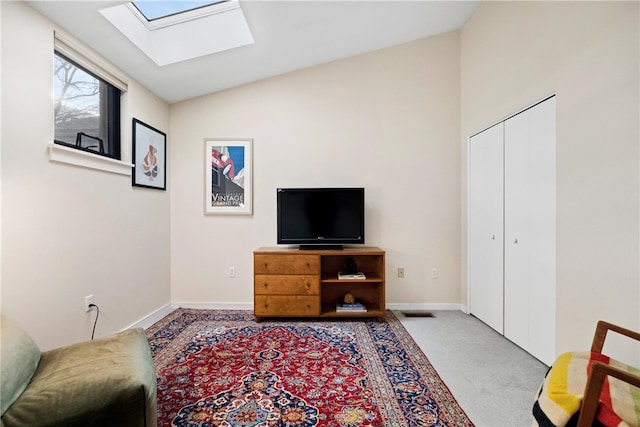 interior space with light carpet and vaulted ceiling with skylight