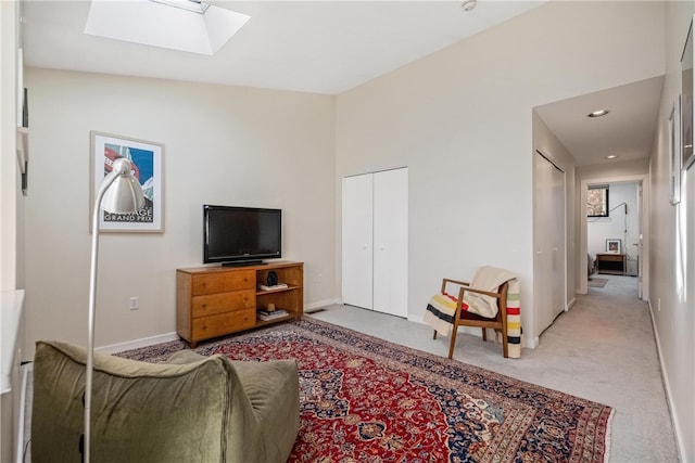 carpeted living room with vaulted ceiling with skylight